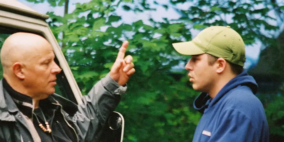 Brad Leslie, cofounder, mid-sentence, one finger raised, a young man in a cap listening
